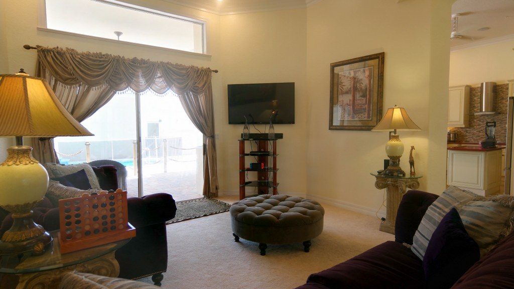 Shared living room with television, seating, and a view through to the pool