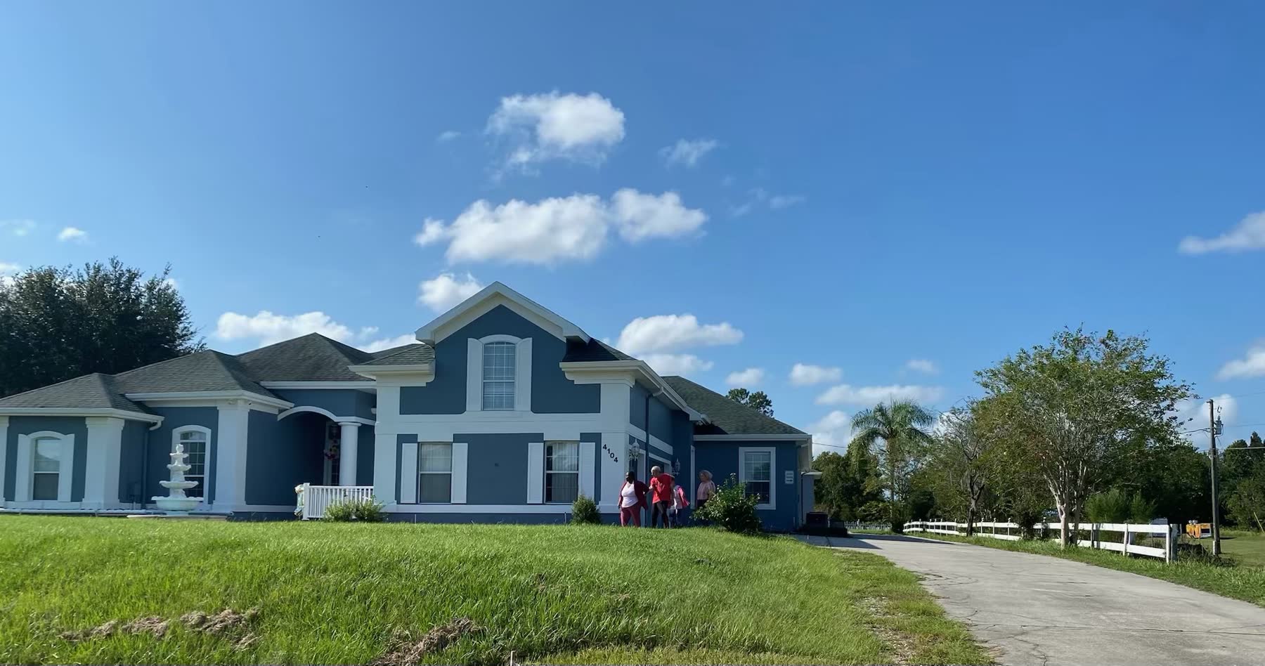 Blue-and-white exterior of the residence beneath a bright sky
