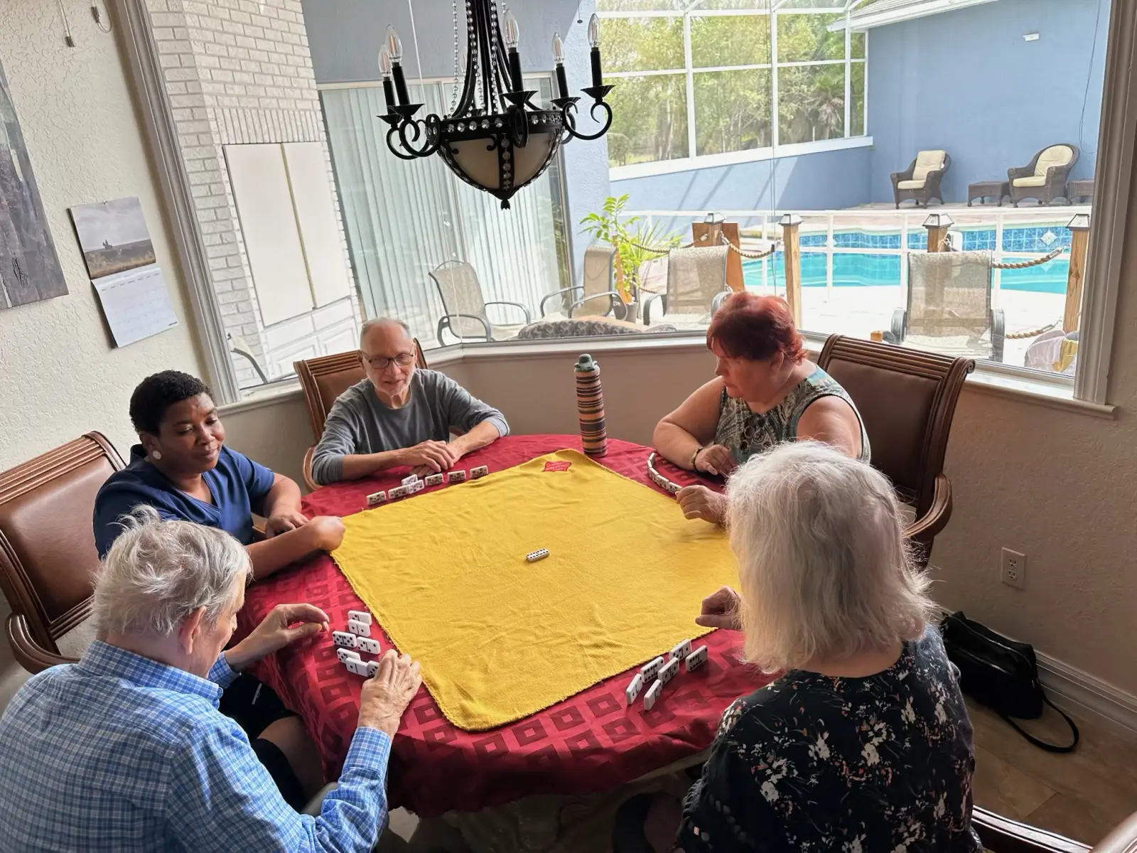 Residents and a caregiver playing dominoes together