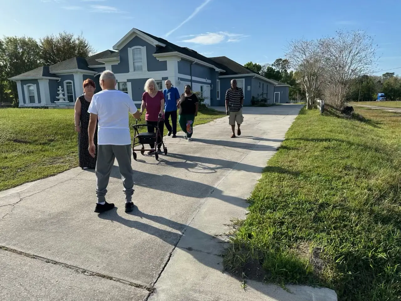 Residents walking up the wide, level driveway to the front of the home